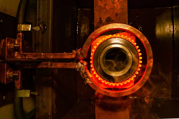 Primer plano calcinación de piezas de engranajes de acero de metal caliente en un horno de inducción de fábrica con humo — Foto de Stock