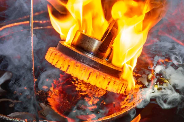 closeup calcining hot metal steel gear parts in a factory induction furnace with smoke