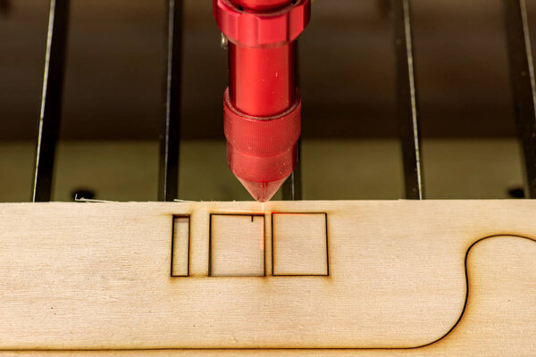 Laser engraver working and engraving wooden board