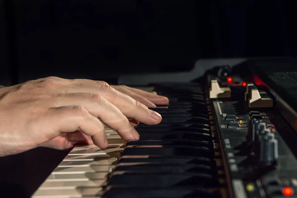 Close-up de mão pessoa tocando um teclado de piano em holofotes — Fotografia de Stock