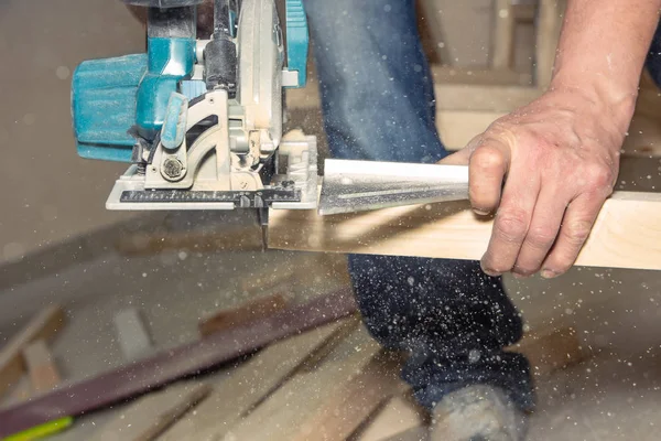 Gros plan l'homme travaille avec la scie à batterie portable sur la surface en bois — Photo