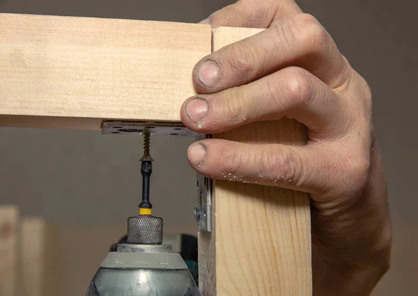 Hombre de primer plano trabaja con destornillador de batería de mano en la superficie de madera — Foto de Stock