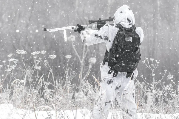 Homme soldat en hiver dans une chasse avec un fusil de sniper en camouflage blanc d'hiver visant debout dans la neige — Photo