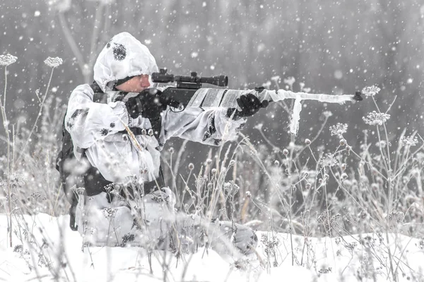 Seorang prajurit di musim dingin sedang berburu dengan senapan sniper dengan kamuflase musim dingin berwarna putih. — Stok Foto