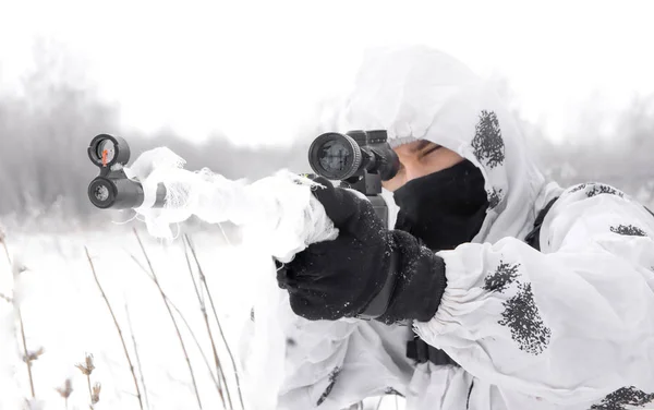Nahaufnahme Porträt Mann Soldat im Winter auf der Jagd mit einem Scharfschützengewehr in weißer Wintertarnung, das in den Schnee zielt — Stockfoto
