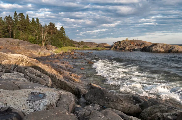 Grosse roche au coucher du soleil mer bleue et forêt au loin — Photo