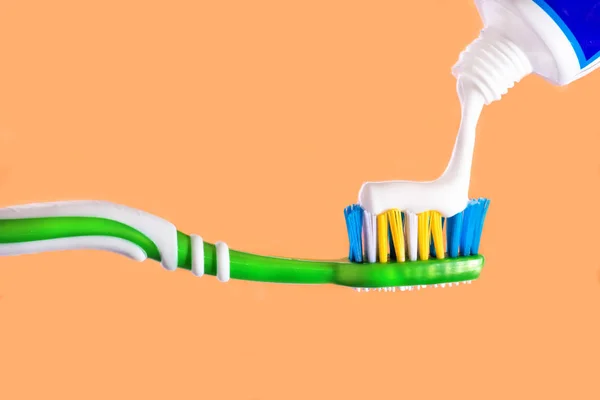 Cepillo de dientes apretado en cepillo de dientes pasta de dientes Fondo naranja — Foto de Stock
