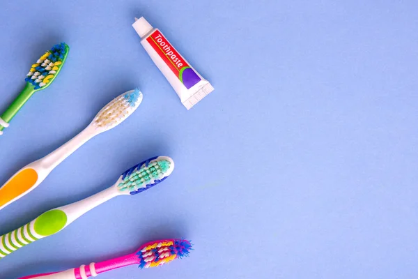 Маленька зубна паста і кілька зубних щіток зверху на синьому — стокове фото