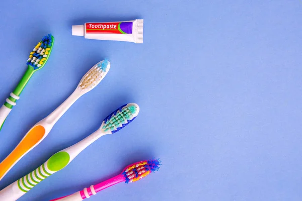 Small toothpaste and several toothbrushes from top view on blue — Stock Photo, Image