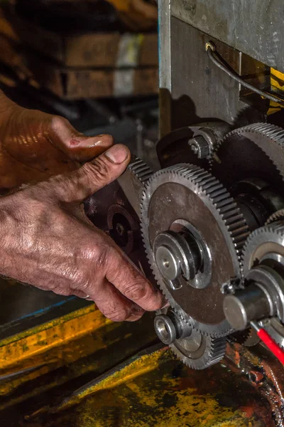 Ruedas metálicas de engranajes con manos de trabajador en primer plano de la máquina industrial — Foto de Stock