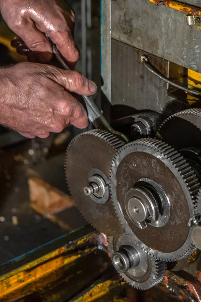 Ruedas metálicas de engranajes con manos de trabajador en primer plano de la máquina industrial — Foto de Stock