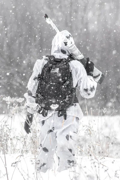 Man soldier in the winter on a hunt with a sniper rifle in white winter camouflage goes to the field Stock Picture