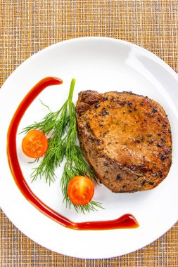 Beyaz bir tabakta domates ve marul salatası yaprak ve çatal ile Biftek et