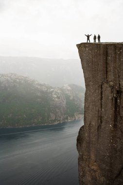 Preikestolen - Norveç'te inanılmaz kaya. Bulutların üzerinde bir uçurumun üzerinde duran kız