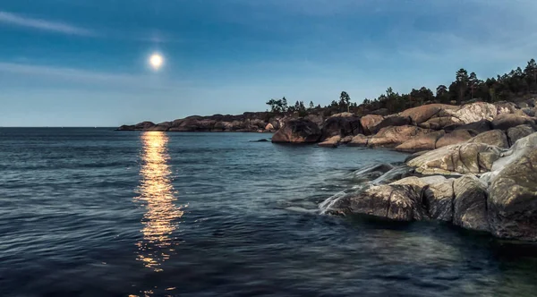 Gran roca al atardecer mar azul y la luz de la luna en la distancia —  Fotos de Stock