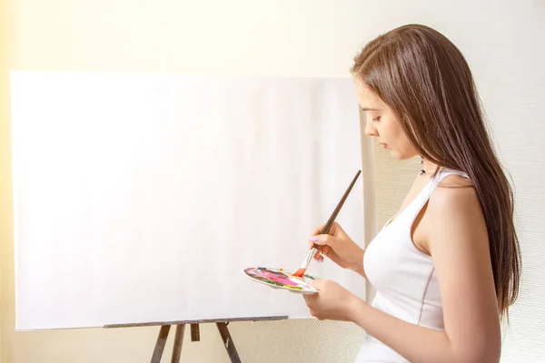 artist painter painting on canvas in a studio. Creative pensive painter girl in workshop. learning painting concept