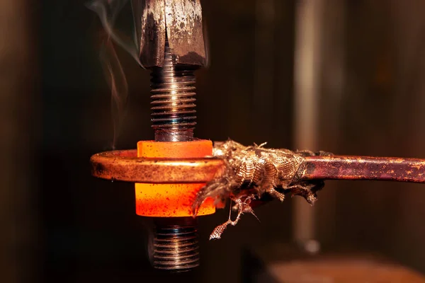 closeup calcining hot metal steel gear parts in a factory induction furnace with smoke