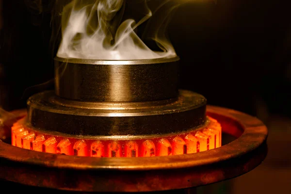 Primer plano calcinación de piezas de engranajes de acero de metal caliente en un horno de inducción de fábrica con humo —  Fotos de Stock