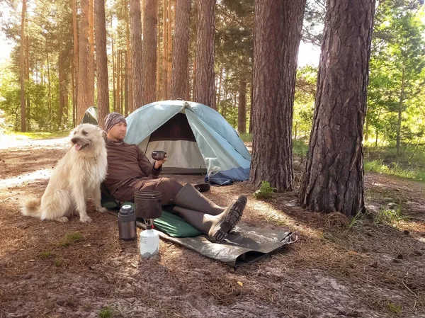 Turist med termos sitter nära tält med sin hund — Stockfoto