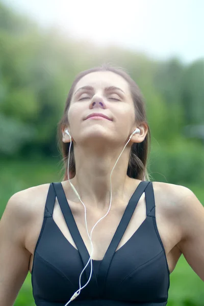 Mujer fitness retrato escuchar y disfrutar de la música en los auriculares en el parque de la ciudad. Concepto fitness y estilo de vida . —  Fotos de Stock