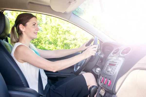 young girl in office clothes driving car, view in the cab with sunlight