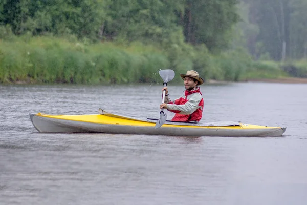 Pohled ze strany na portrét Kayaker v kulatého klobouku na letní říční krajině s těžkým deštěm — Stock fotografie