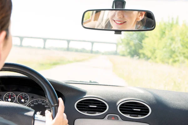 운전 자동차, 후면 보기, 얼굴의 전반사 거울에 젊은 명랑 한 여자 — 스톡 사진
