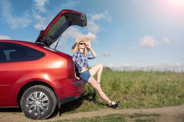 yan görünümü büyük bir şapka üzerinde arabanın yanında duran güzel kız