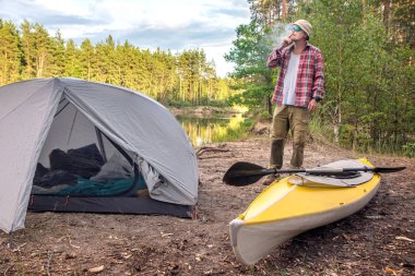 adam poz ve açık kamp çadırı ve sarı kaya yakınında sigara