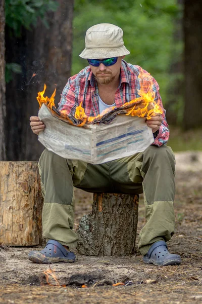 Turista sentado en el muñón y leyendo un periódico en llamas en —  Fotos de Stock