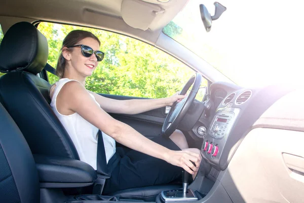 young girl in office clothes and sunglasses driving car, view in