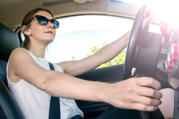 young girl in office clothes and sunglasses driving car, view in