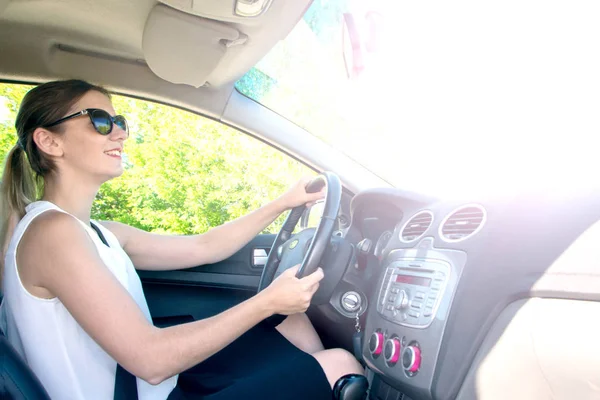 young girl in office clothes and sunglasses driving car, view in