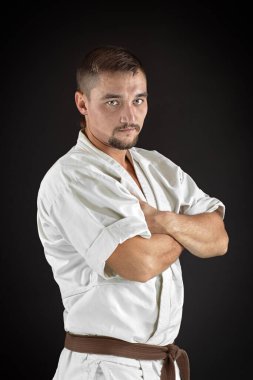 Geleneksel kimono eğitimi almış ve siyah arka planda poz veren bir karateci.