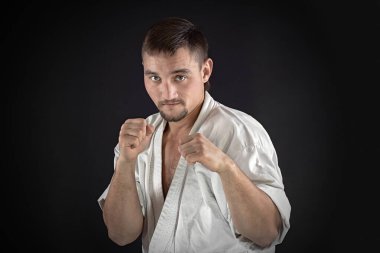 Geleneksel kimono eğitimi almış ve siyah arka planda poz veren bir karateci.