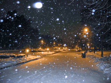 Winter park geceleri. Kar yağışı ve turuncu ışık fenerler