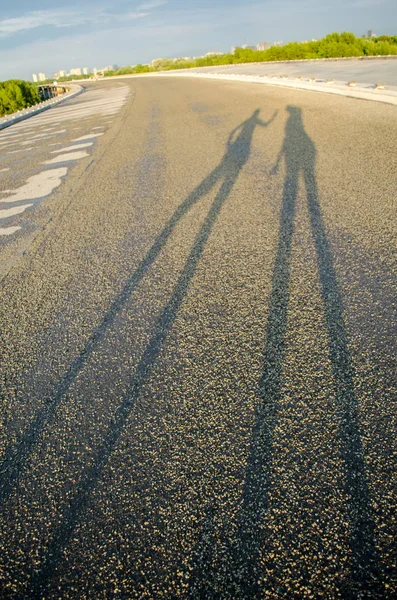 Shadow of two strange people on the road