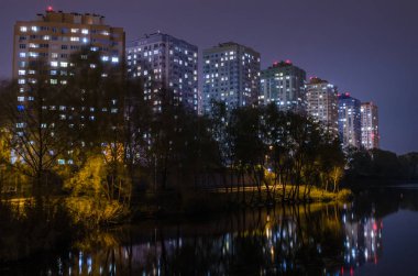 Apartmanlar ile gece gölette yakınındaki parlayan pencere eşiği