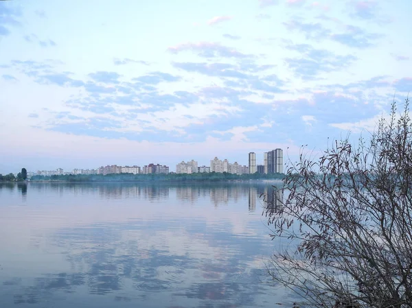 City Kiev skyline. View of the sleeping area across the river. Clouds reflected in water
