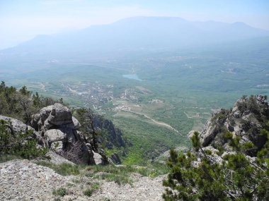 Beautiful mountain landscape with top view of a distant valley with lake. Distant mountain plateaus in a blue haze. Crimean mountains