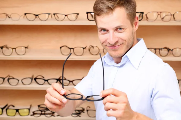 Prescription glasses. The man chooses spectacle frames in the optical salon