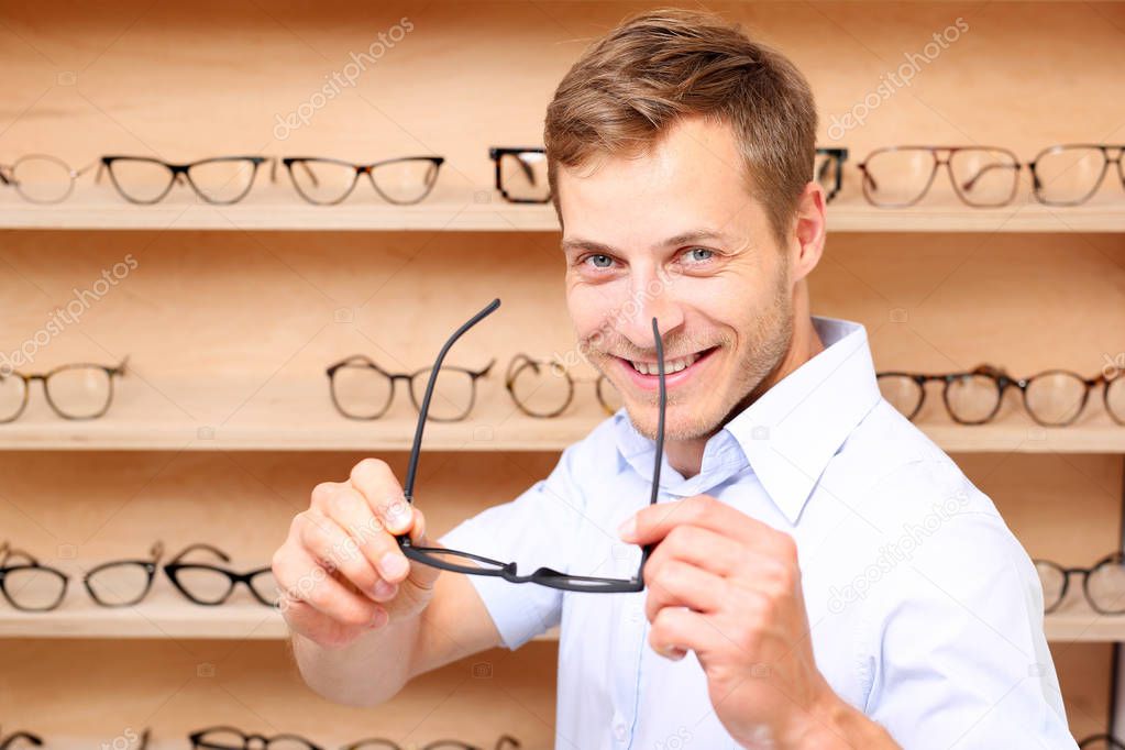 Facial glasses. The man chooses spectacle frames in the optical salon