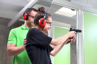 Atış poligonuna. Kadın silah bir eğitmen gözetiminde çekim mesafeden ateş eder.