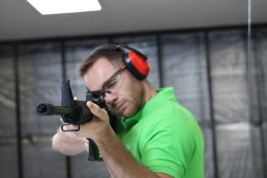 Adamın tüfeğinden vuruyor. Yakışıklı adam trenler aralığı atıcılık spor çekim.