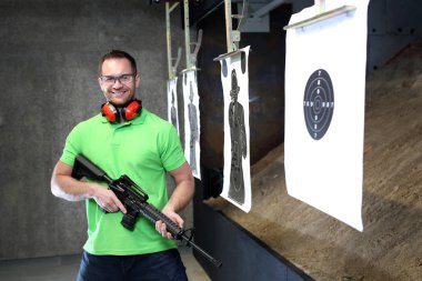 Adamın tüfeğinden vuruyor. Yakışıklı adam trenler aralığı atıcılık spor çekim.