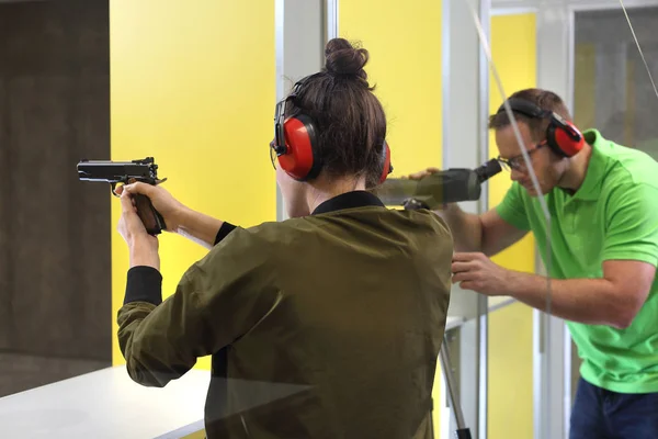 Shooting range. A woman shoots a rifle. The woman shoots from the gun at the shooting range under the supervision of an instructor.