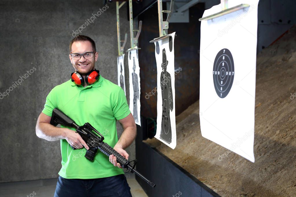 The man shoots from the rifle. Handsome man trains shooting at the sports shooting range.
