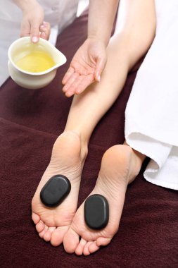 Taşlar ile masaj. Bazalt taşlarla, rahatlatıcı spa salonda kadın ayakları.