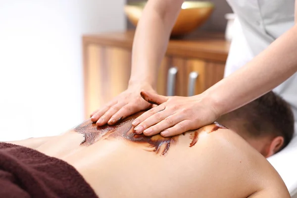 Chocolate back massage. A man on a massage treatment in a wellness salon