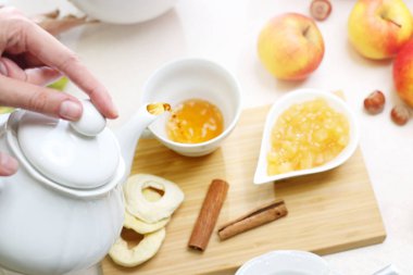 Çay. Bir kadın, bir fincan içine çay dökülen. Tarçın ve kuru meyveler ilavesi ile elma reçel ile sonbahar aromatik çay